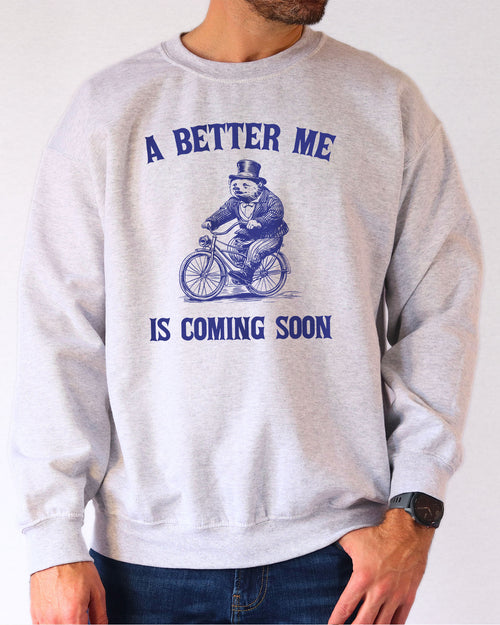 Model wearing ash color sweatshirt with 'A Better Me Is Coming' graphic design